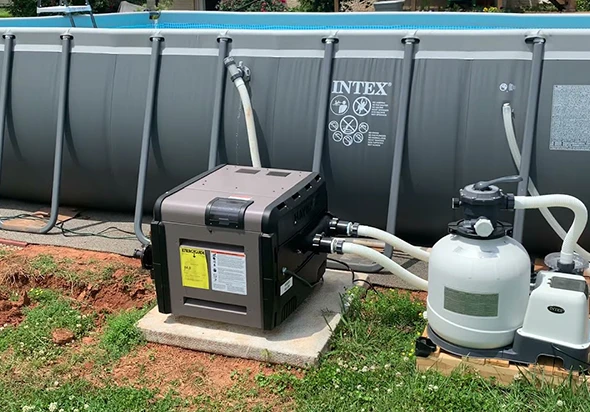 An above-ground pool heater and filtration system next to a pool.