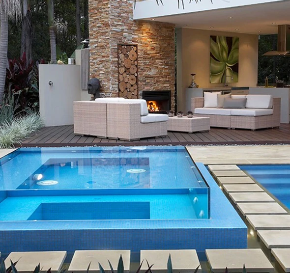 A luxurious swimming pool and spa area with a fireplace and comfortable seating.