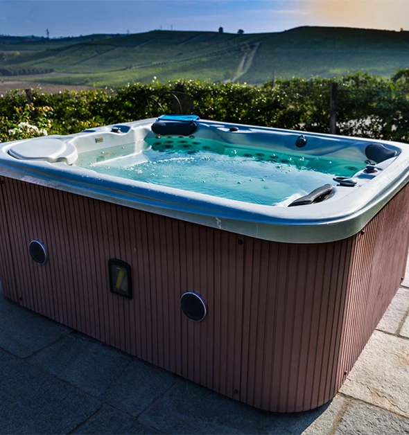 A hot tub with jets bubbling, overlooking a vineyard at sunset.