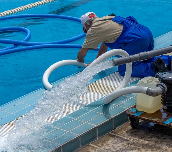A pool technician working on the filtration system of a swimming pool.