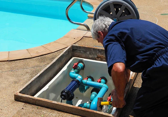 A pool technician working on the pool's mechanical system in an underground vault.