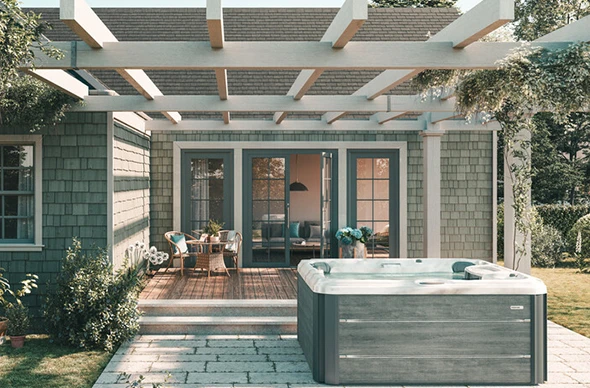 A modern hot tub under a louvered pergola, with lounge chairs and landscaping.