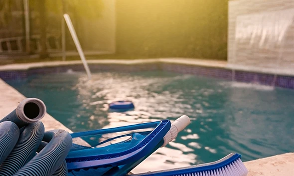 A pool technician performing maintenance on pool equipment next to a pool.